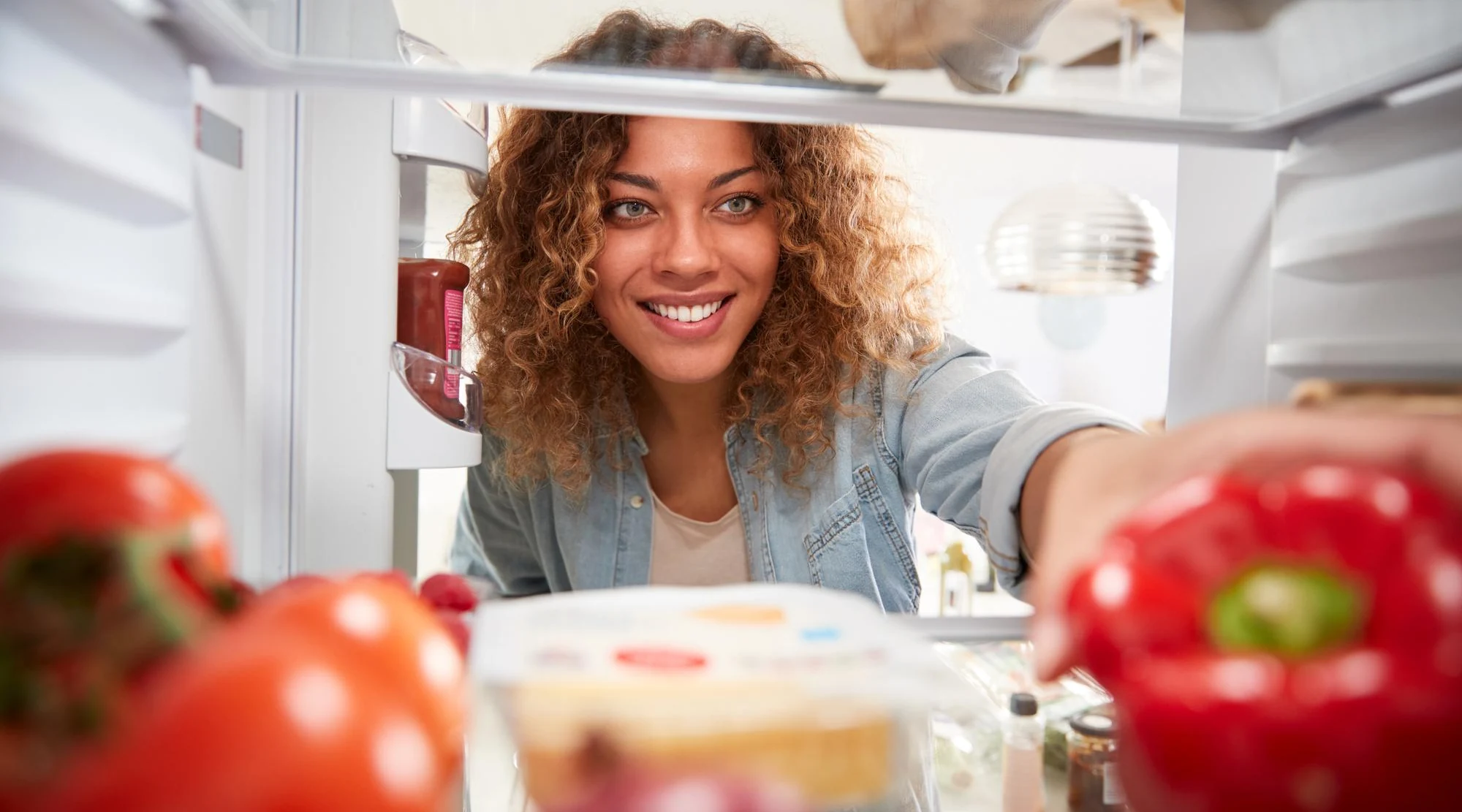 Mulher sorrindo diante do refrigerador de embutir aberto